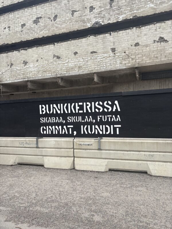 Purkutyömaa-aita tekstillä "Bunkkerissa skabaa,skulaa,futaa gimmat, kundit"