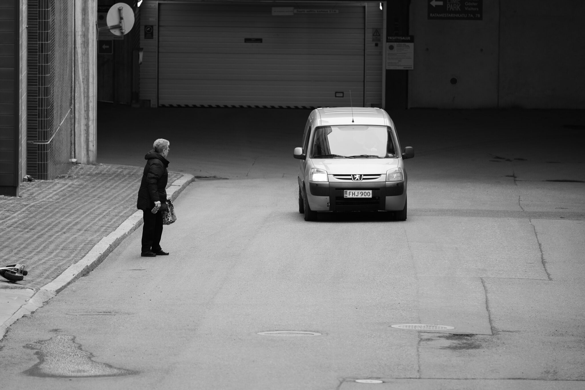 Vanhemmanpuoleinen henkilö väistää ohikulkevaa autoa.