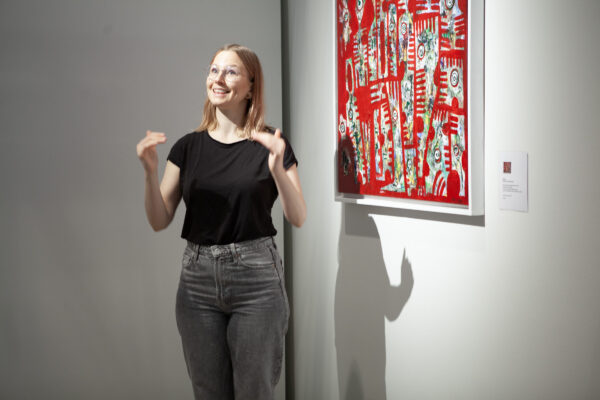 Maku Dakarin punainen taulu on sommiteltu abstraktisti ja yksityiskohtaisesti. Aino Laiho on viittomassa teoksen taustoja.