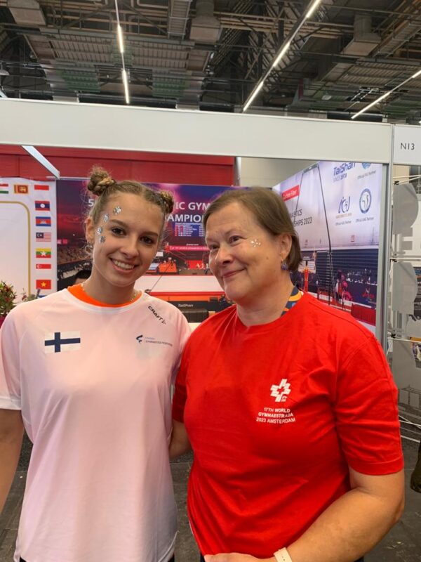 Kuvassa kaksi voimistelijaa, jotka ovat vaihtaneet urheilupaitoja toistensa kanssa.