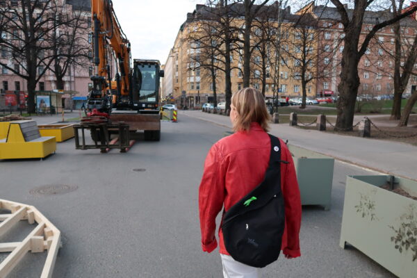 Punaisiin pukeutunut Tanja-niminen henkilö kävelee Karhupuiston kulmalla. Kuva on takaapäin otettu.