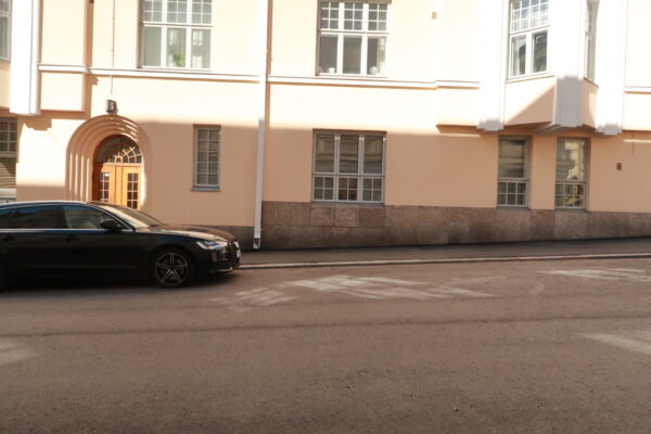 Katu Kruununhaassa iltapäivällä. Keltainen seinä ja auto vasemmalla.